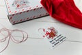 Christmas gift and Santa hat on white wooden table. Inscription on the card: Happiness is snow, sweets and warm mittens.