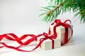 Christmas gift in white box with red ribbon on light background with fir tree. New year holiday composition. Copy Space For Your T Royalty Free Stock Photo