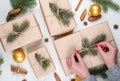 Christmas gift wrapping background, copy space. Female hands holding christmas present box wrapped in kraft, top view. Royalty Free Stock Photo