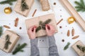 Christmas gift wrapping background. Female hands packaging christmas present wrapped in kraft paper, top view. Royalty Free Stock Photo