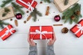Christmas gift wrapping background. Female hands packaging red christmas present box, top view. Winter holidays concept. Royalty Free Stock Photo