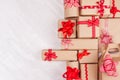 Christmas gifts background - various craft paper gifts with red ribbons and bows on soft light white wood board, flat lay. Royalty Free Stock Photo