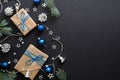 Christmas gifts with blue ribbon, blue balls, fir tree branches, cones, confetti on dark black background with copy space. Flat Royalty Free Stock Photo