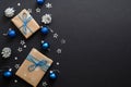 Christmas gifts with blue ribbon, blue balls, fir tree branches, cones, confetti on dark black background with copy space. Flat Royalty Free Stock Photo