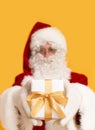 Blurred Santa Claus holding holiday present over orange