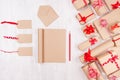 Christmas gifts boxes, blank labels and notepad for your text of kraft paper with red bows and ribbon on soft white wood board. Royalty Free Stock Photo