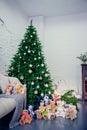 Cute little boy sitting down by the decorated Christmas tree with toys, teddy bears and gift boxes Royalty Free Stock Photo