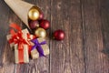 Christmas gifts, gold, silver, red Christmas balls spilled out from a package of kraft paper on a wooden background. Christmas bal Royalty Free Stock Photo