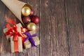 Christmas gifts, gold, silver, red Christmas balls spilled out from a package of kraft paper on a wooden background. Christmas bal Royalty Free Stock Photo