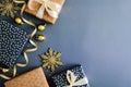 Christmas gifts with golden baubles, snowflakes and ribbon on dark blue background. Flat lay, top view, copy space Royalty Free Stock Photo