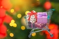 Christmas gifts and presents ribbon gift box in shopping trolley cart with blurred lights