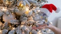 Christmas gifts shopping time. Woman holding a shopping trolley in a santa claus hat by the christmas tree. Royalty Free Stock Photo