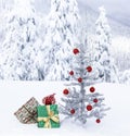 Christmas gifts under artificial tinsel tree outdoors with snowy mountain landscape background. Actual photo shot in winter