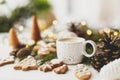 Christmas gingerbread cookies, coffee, pine cones and warm lights on white wooden table