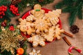 Christmas gingerbread cookies homemade in red plate with branches of Christmas tree and New Year decor on table with burlap tablec