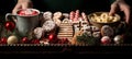 Christmas gingerbread cookies on tray with Christmas snacks: candies, cocoa, Christmas tree branches. Female hands. Horizontal