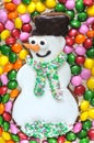 Christmas gingerbread funny snowman on a background of multi-colored candies. Top view, natural light Royalty Free Stock Photo