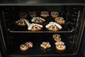 Christmas gingerbread house shaped cookies with white snow icing baking in the oven. Homemade festive traditional gingerbread men Royalty Free Stock Photo