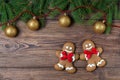 Christmas gingerbread men on wooden background with fir frame with golden balls, top view Royalty Free Stock Photo