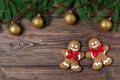 Christmas gingerbread men on wooden background with fir frame with golden balls, top view Royalty Free Stock Photo