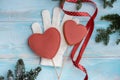 Christmas gingerbread on a white mitten. on a blue wooden background. New Year card. Red heart on a stick. sweet candy