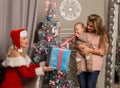 Christmas girl giving presents to little baby. woman dressed as Santa Claus Royalty Free Stock Photo
