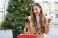 Christmas girl. Happy excited young woman with shopping bags in her hand buying christams presents with her smart phone outdoors Royalty Free Stock Photo