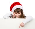 Christmas girl with santa hat standing behind white board. Royalty Free Stock Photo
