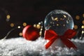 Christmas glass globe with artificial snow on blurred background. Royalty Free Stock Photo