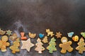 Christmas glazed cookies lie along the bottom edge on a black shabby background