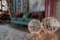 Christmas glowing garland on shape of balls. Beautiful lighting lamps. Colorful lights , green sofa in living room