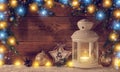Christmas glowing lantern with lights garlands on a wooden background