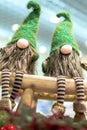 Christmas gnomes in green caps and striped pants. Sit on a wooden bench. Christmas. Holiday