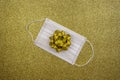 Christmas gold deco baubles on golden background with surgical protective mask. New year on quarantine. Flat lay design. Copy