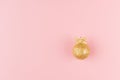 Christmas golden decoration as simple festive bright background - gold glittering ball with ribbon on pastel pink color, top view. Royalty Free Stock Photo