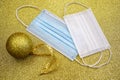 Christmas golden decorative ball on golden background with two surgical protective masks: for adult and for child. New year on