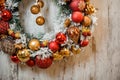 Christmas green artificial wreath covered with white snow with golden and red decoration in the left corner Royalty Free Stock Photo