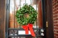 Christmas green wreath with red ribbon on the front door. Entrance to the house decorated for the winter holiday - Xmas and New Royalty Free Stock Photo