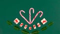 Christmas greeting card. ÃÂ¡andy canes decorated with gift boxes and sprigs of spruce on viridian green background