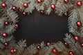 Christmas greeting card in black background. Frame of fir branches decorated with red balls Royalty Free Stock Photo