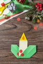 Christmas greeting card gift origami candle on wooden table. Childrens art project, handmade, crafts for kids