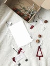 Christmas greeting card mockup, empty white postcard with space for text and modern festive glass ornaments on white soft blanket