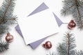 Christmas greeting card mockup with envelope, green fir tree branches and balls on white wooden background, top view, flat lay. Royalty Free Stock Photo