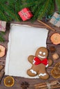 Christmas greeting card, old blank paper sheet, gingerbread man with frame made of fir, and spices, wooden background Royalty Free Stock Photo