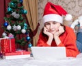 Christmas greetings on the Internet, education, online shopping. Girl in a Santa Claus cap with a laptop at home Royalty Free Stock Photo