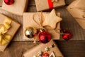 Christmas handmade gift boxes decorated with craft paper and red gold balls and handmade cookie star on vintage wooden background Royalty Free Stock Photo