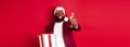 Christmas. Handsome african american man in party glasses and santa hat, holding new year gift and glass of champagne Royalty Free Stock Photo