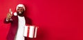 Christmas. Handsome african american man in party glasses and santa hat, holding new year gift and glass of champagne Royalty Free Stock Photo