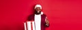 Christmas. Handsome african american man in party glasses and santa hat, holding new year gift and glass of champagne Royalty Free Stock Photo