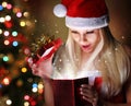 Christmas. Happy Blonde Girl with Santa Hat Opening Gift Box Royalty Free Stock Photo